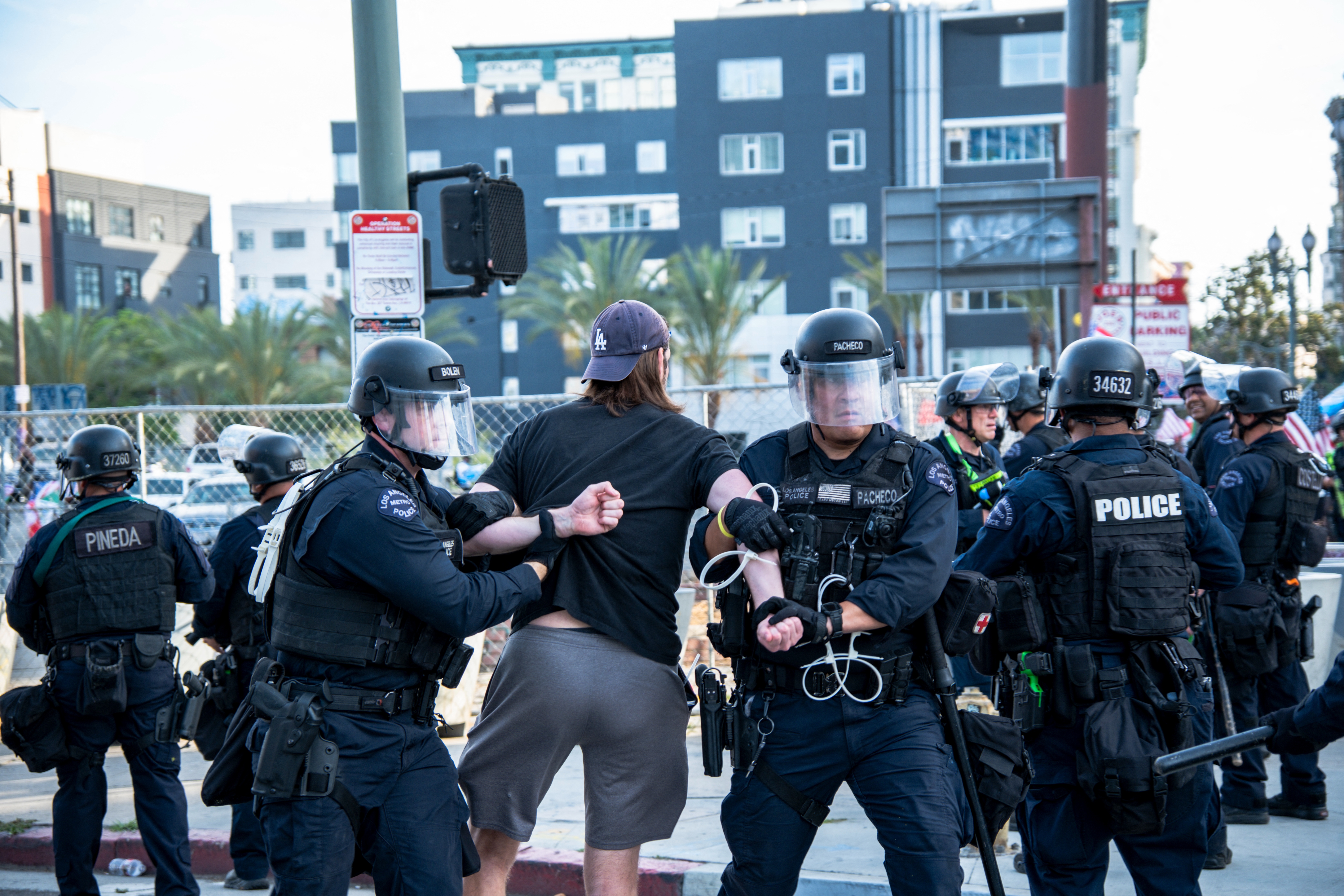 Police officers detain a protester on a city street amid other officers and bystanders