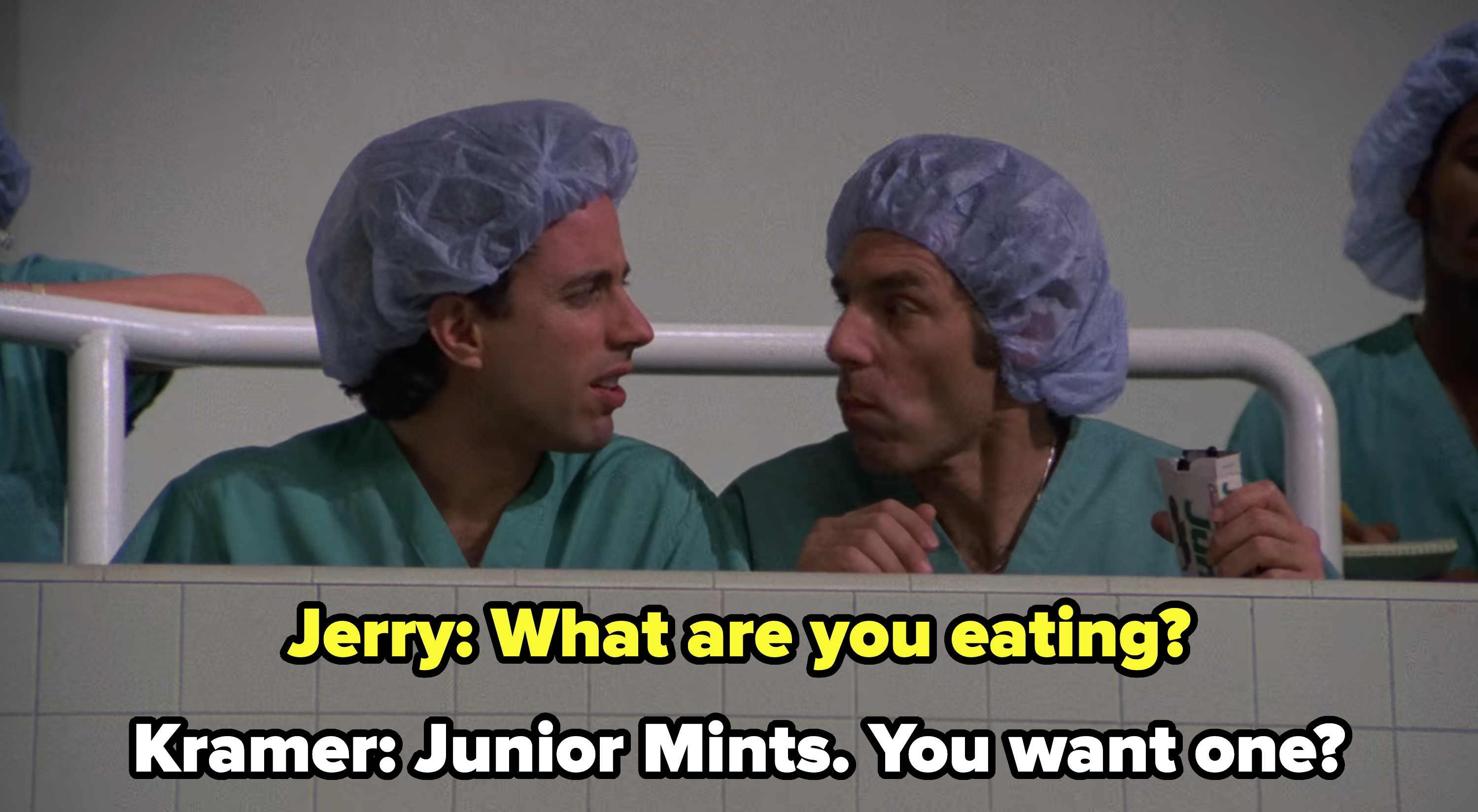 sitting in the surgery gallery in scrubs and hairnets, Kramer offers Jerry a Junior Mint