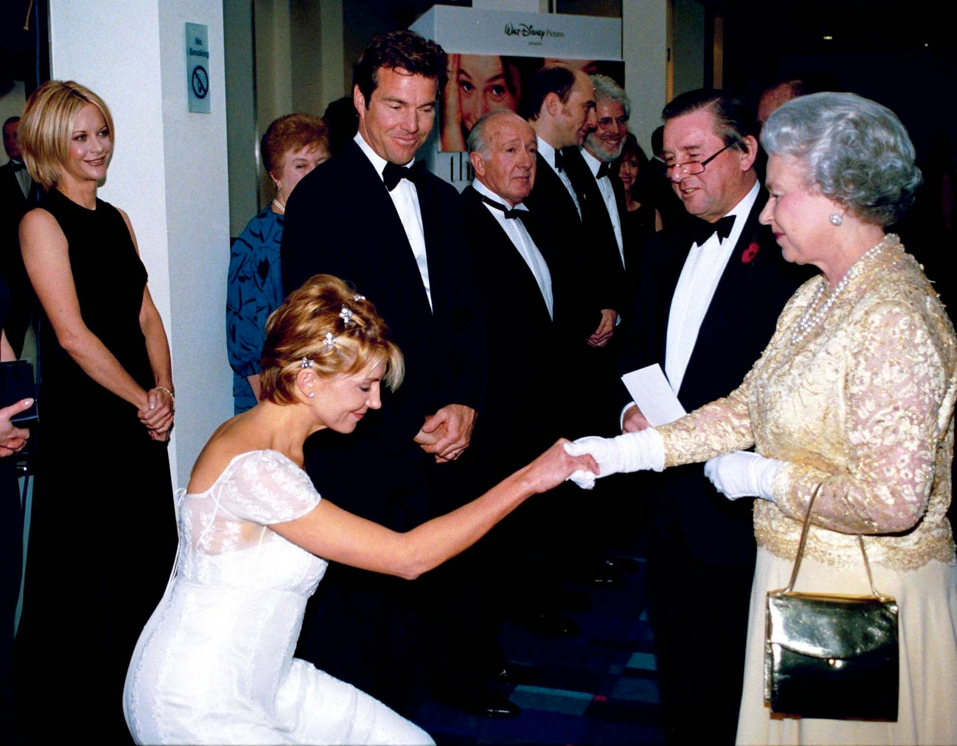 A pistillate successful an elegant achromatic gown curtsies to an older pistillate successful a beaded formal with gloves, shaking hands. People successful ceremonial attire ticker nearby