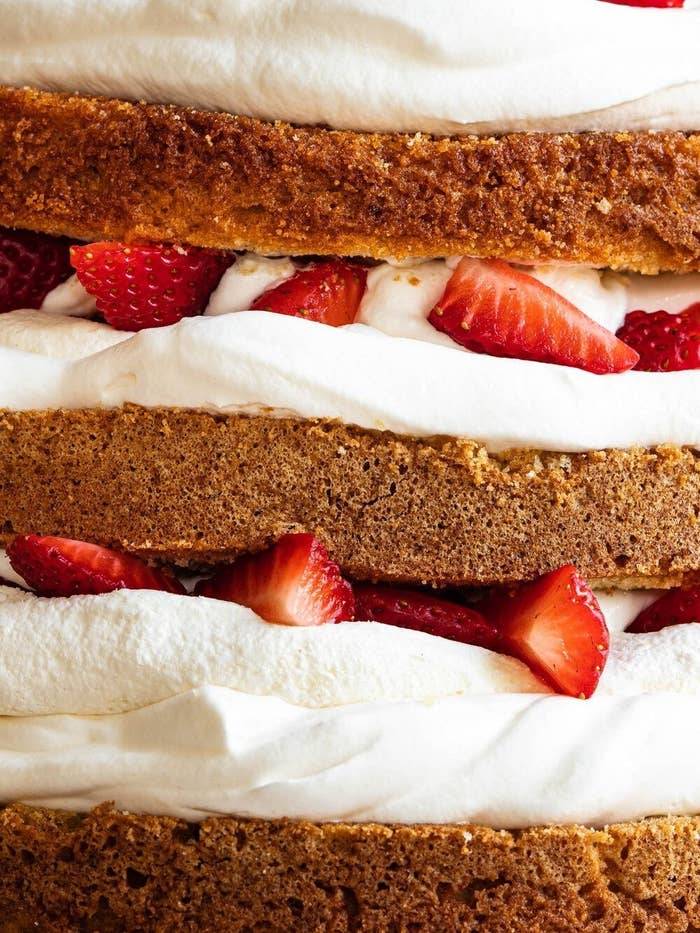 Un pastel de capas con crema y fresas frescas intercaladas, mostrando una textura esponjosa y un aspecto apetitoso
