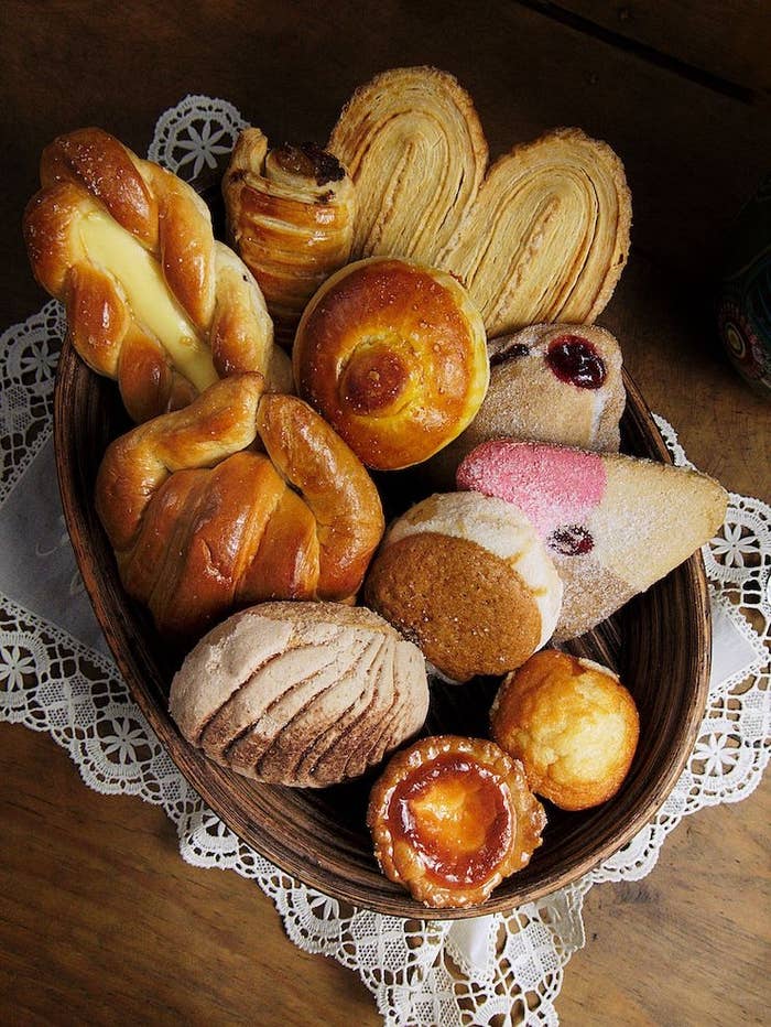 Variedad de panes dulces mexicanos en una canasta sobre una mesa de madera