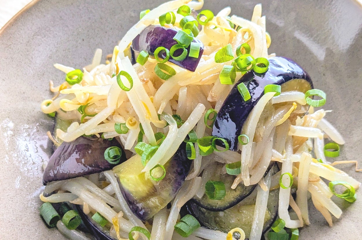 もやしとナスの炒め物が皿に盛られており、ネギがトッピングされています。