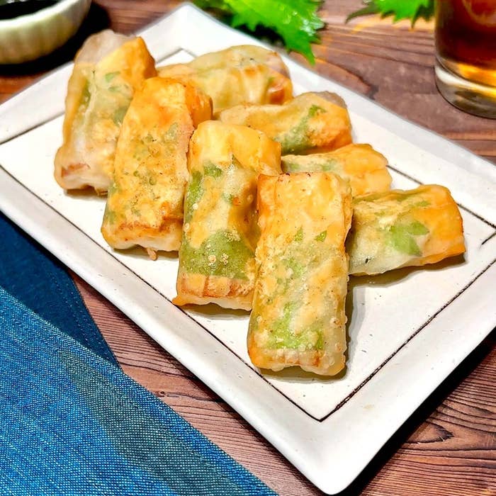 白い皿に盛られた春巻きのような揚げ物。テーブルには醤油の小皿と飲み物が置かれている。