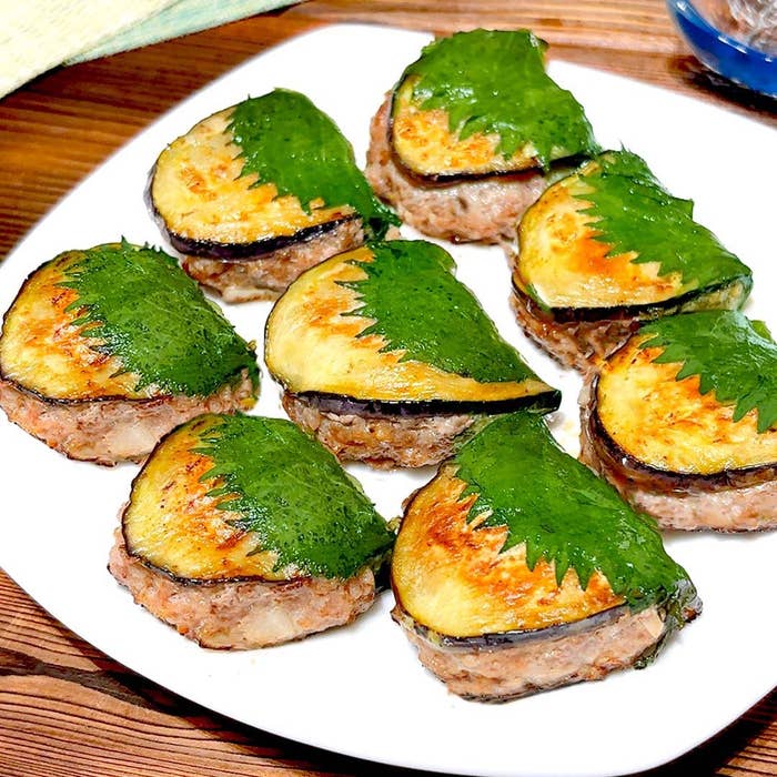 皿に盛られたナスと肉の重ね焼き。シソの葉がトッピングされている。