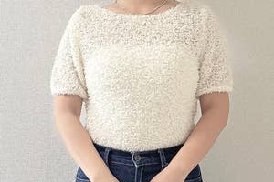 女性がシンプルでカジュアルなニットとジーンズを着用している姿。