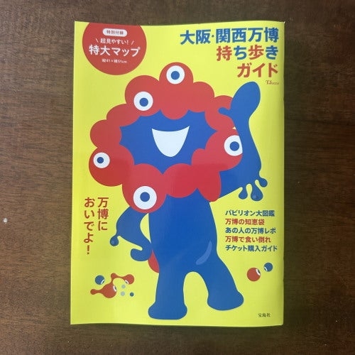 青いキャラクターが描かれた大阪・関西万博持ち歩きガイドの表紙。案内情報がまとめられている。