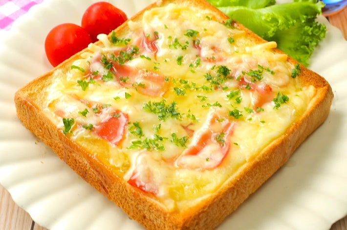 トーストに溶けたチーズとハムが乗っており、レタスとミニトマトが添えられた美味しそうな朝食プレート。