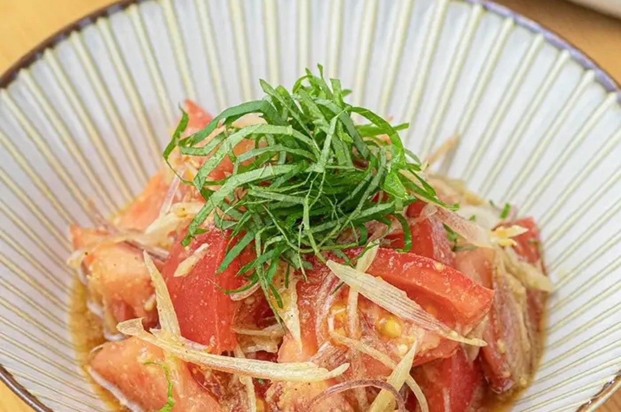 トマトと玉ねぎのサラダにハーブがトッピングされた料理が皿に盛られている。