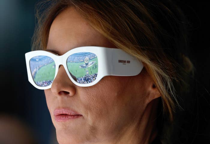 Person wearing large sunglasses reflecting a sports stadium scene, focusing intently. The image captures a moment of reflection and anticipation