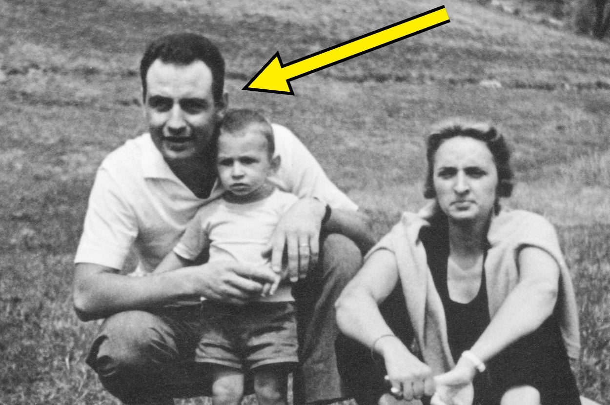A vintage photo of three people sitting outdoors, with an arrow pointing at the man. The group includes a man, a child, and a woman