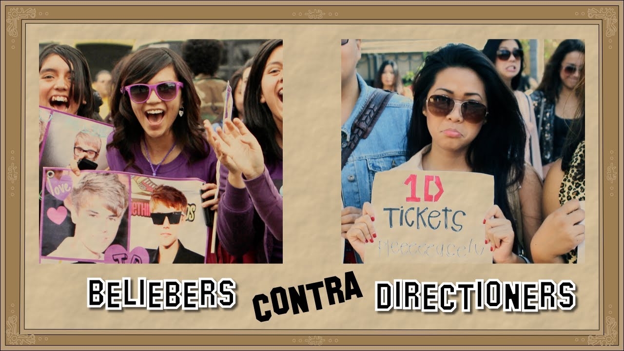 Mujeres sostienen carteles comparando &quot;Beliebers&quot; con &quot;Directioners&quot;, reflejando rivalidad entre seguidores de Justin Bieber y One Direction