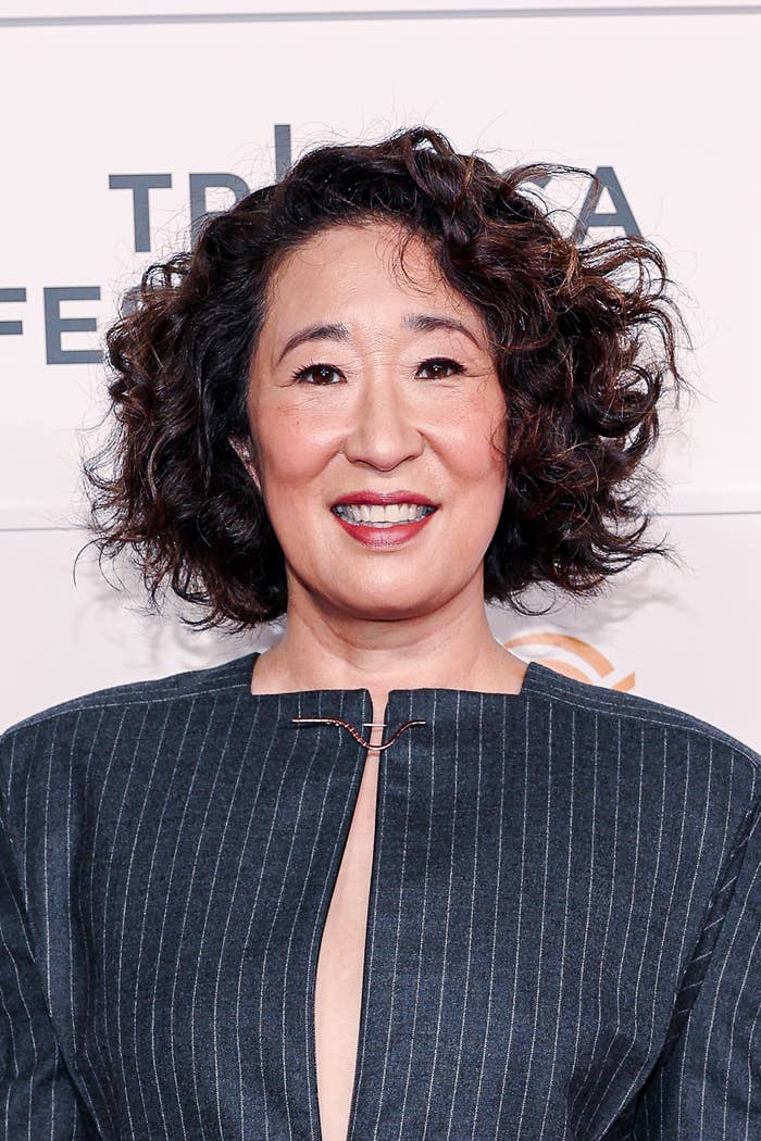 Person with curly hair wearing a pinstripe jacket smiles at the Tribeca Festival