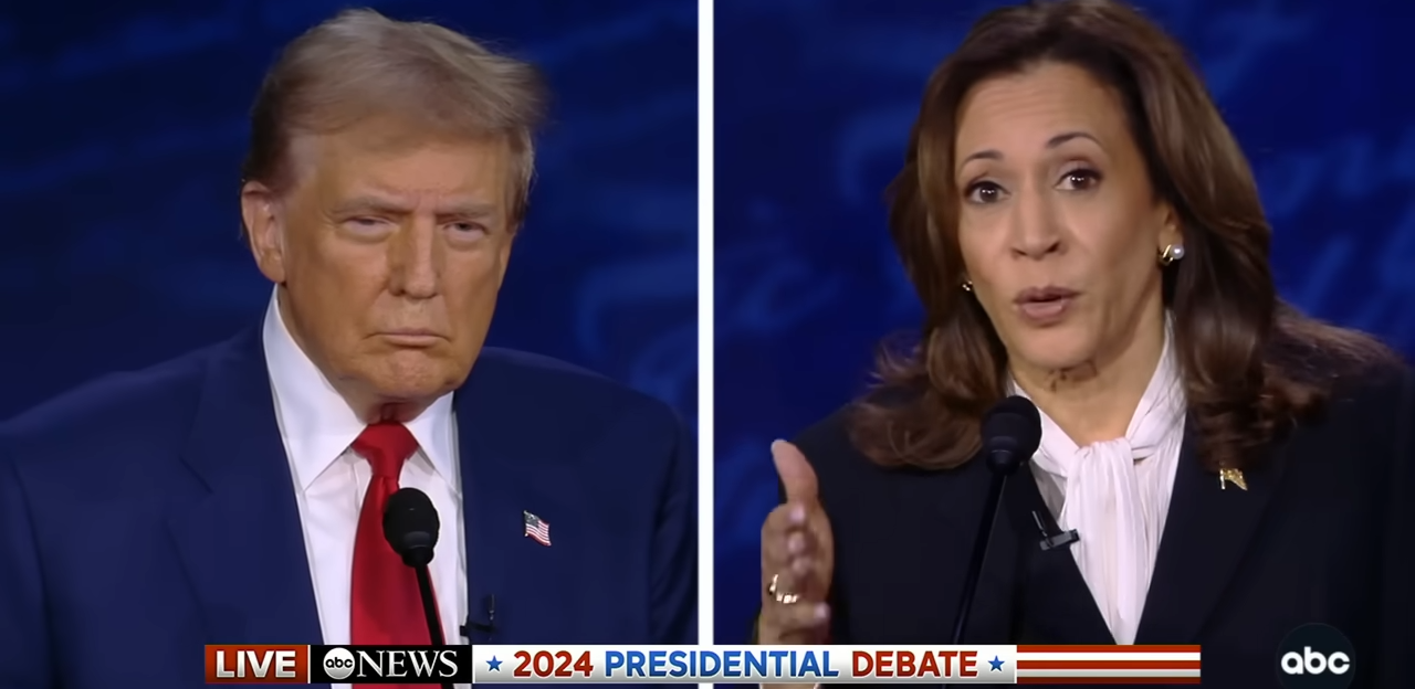 Two political figures at the 2024 presidential debate, both in suits, speaking on stage with a news header below