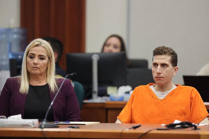 A person in an orange jumpsuit sits beside a woman in a courtroom setting, both appearing attentive