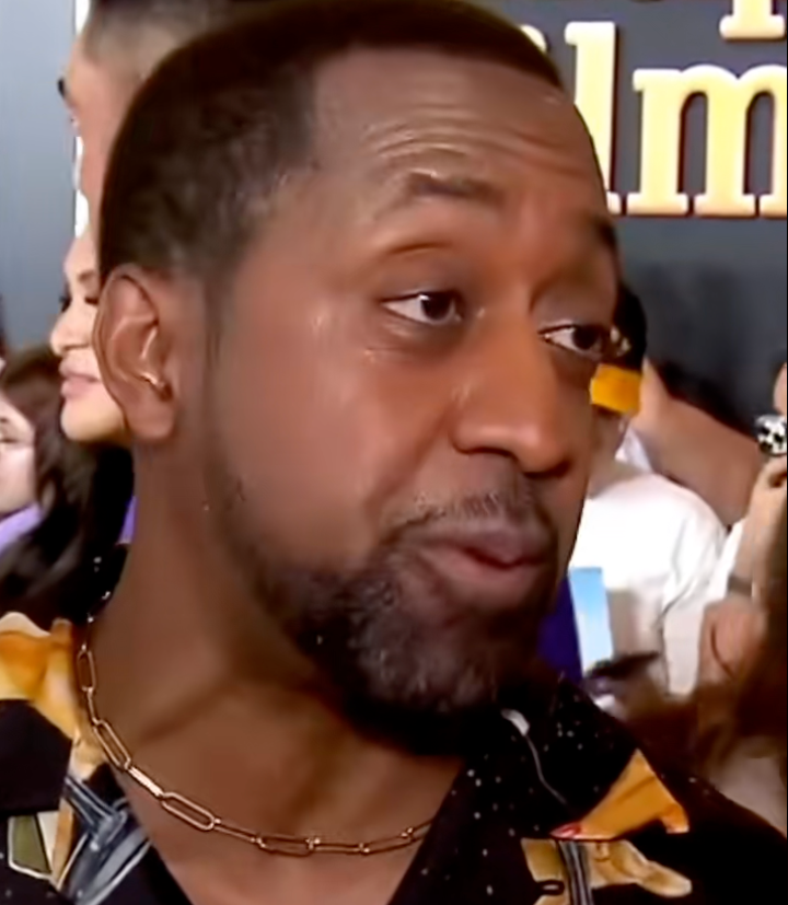 Jaleel White on a red carpet in a patterned shirt and necklace, speaking and gesturing slightly