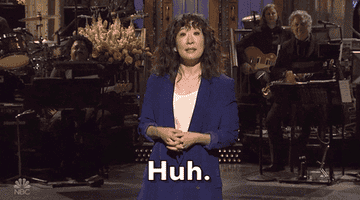 A person in a blue blazer stands on stage, speaking to an audience. The text reads &quot;Huh.&quot;