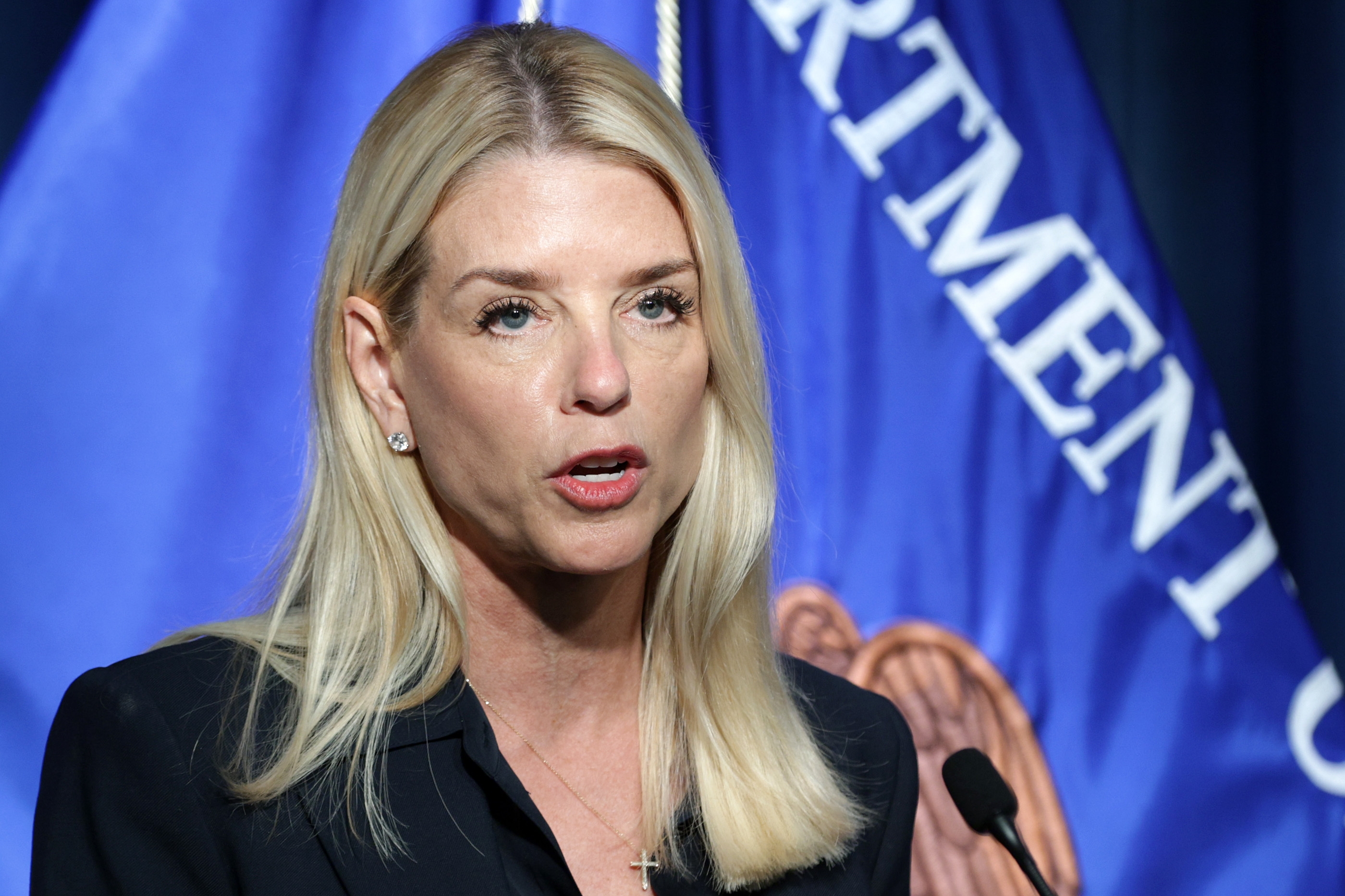 A person speaking at a podium with a U.S. Department of Justice flag in the background