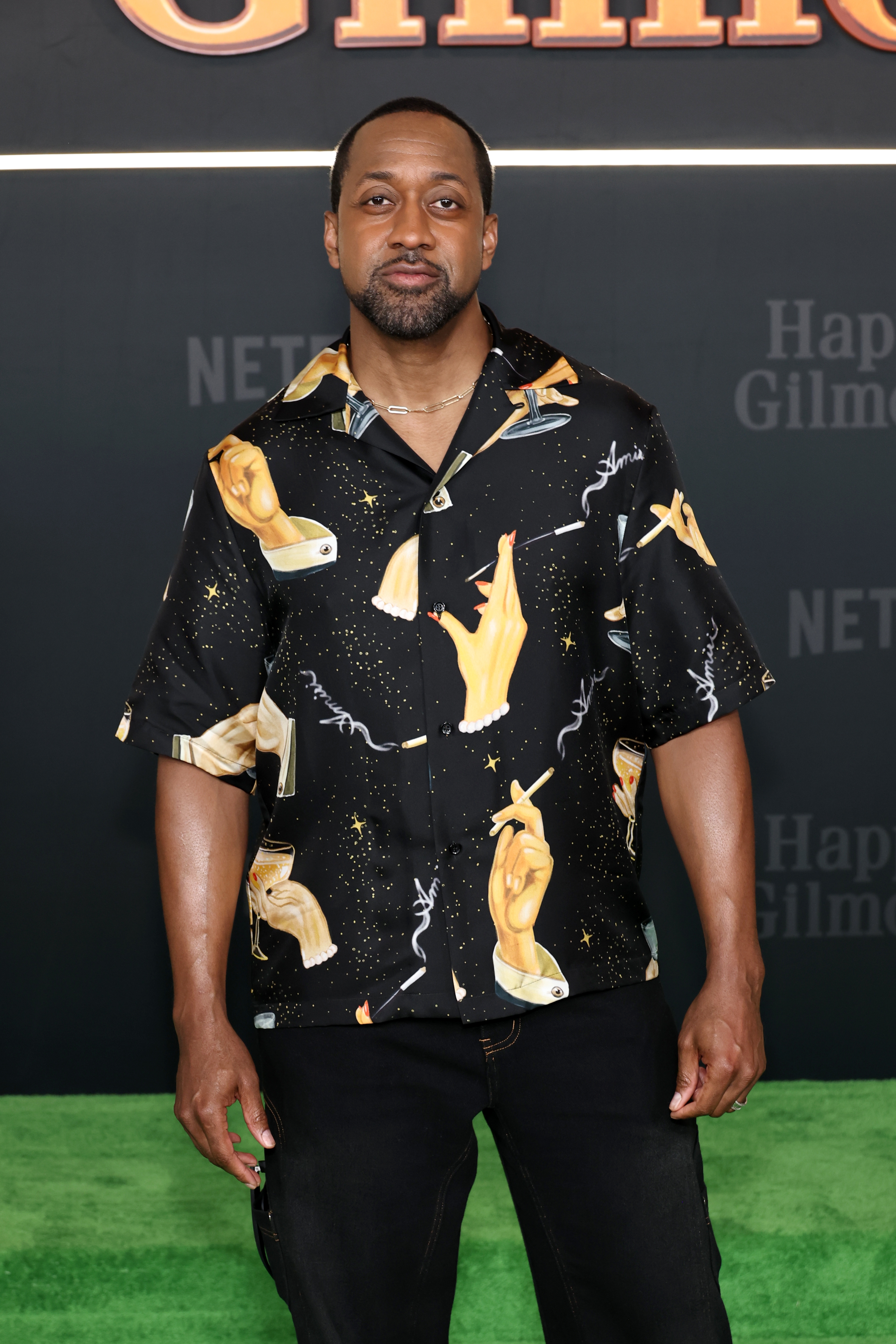 Jaleel White on carpet wearing a shirt with artistic hand designs, attending a "Happy Gilmore 2" event