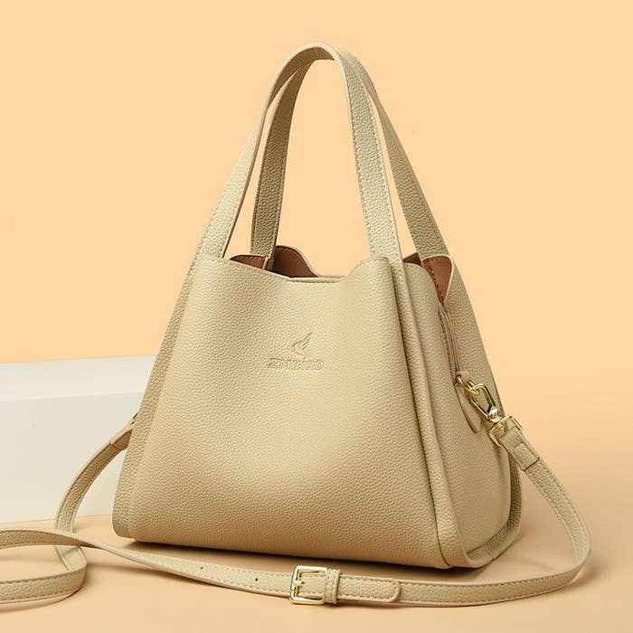Bolso de mano beige con correas ajustables, diseño minimalista y logo en el centro. Ideal para artículos sobre hallazgos de moda en Internet
