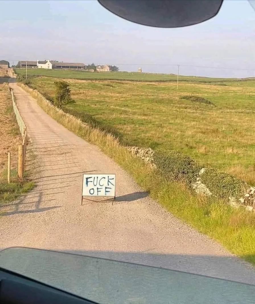 A rural road sign with large text says, “FUCK OFF.”