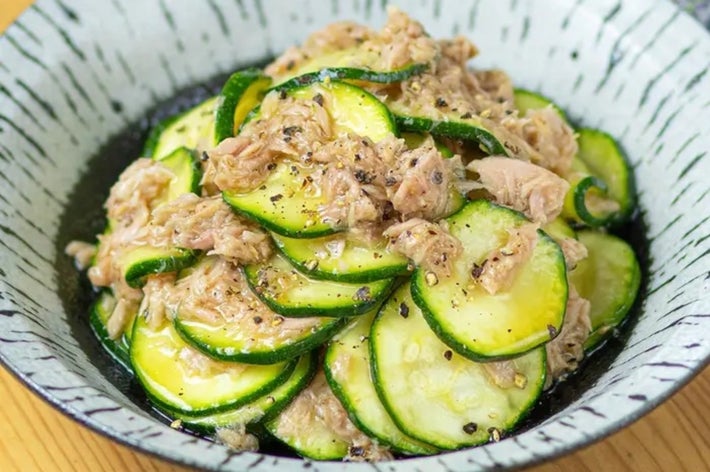 ズッキーニとツナが盛られた白いボウルに入った料理。ローズマリーの枝が背景に置かれている。