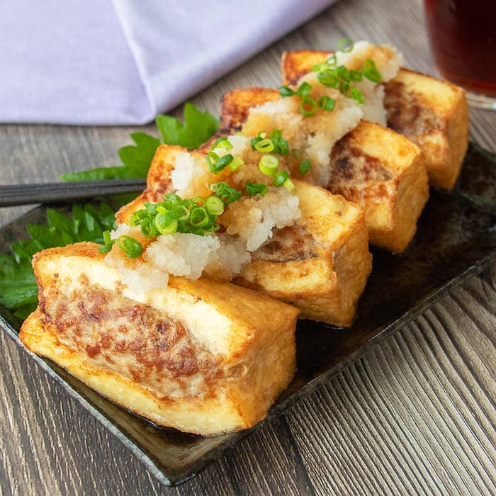 和風の皿に盛り付けられた肉詰め厚揚げ豆腐に大根おろしとポン酢しょうゆ、小ネギがのっている。