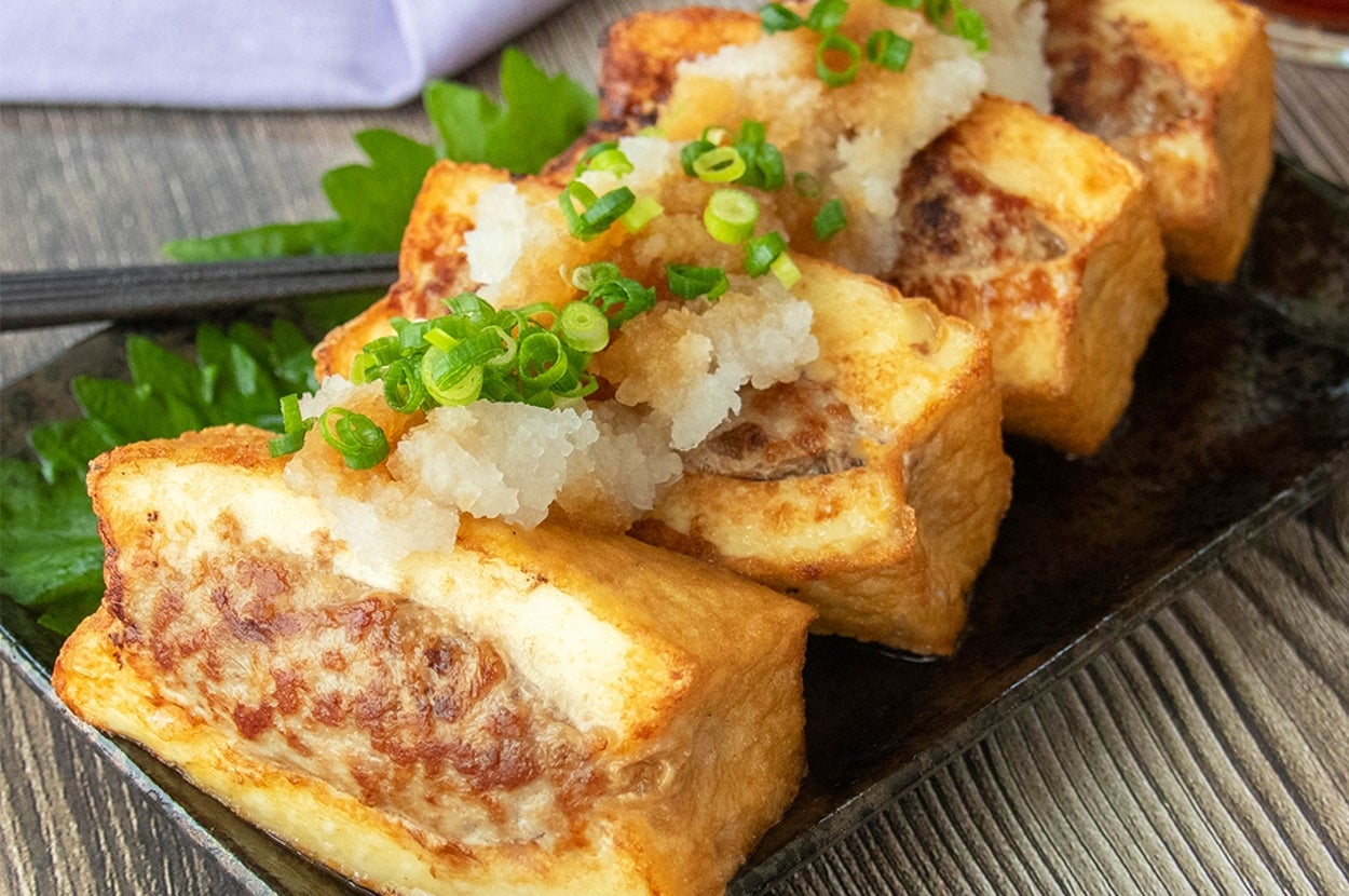 和風の皿に盛り付けられた肉詰め厚揚げ豆腐に大根おろしとポン酢しょうゆ、小ネギがのっている。