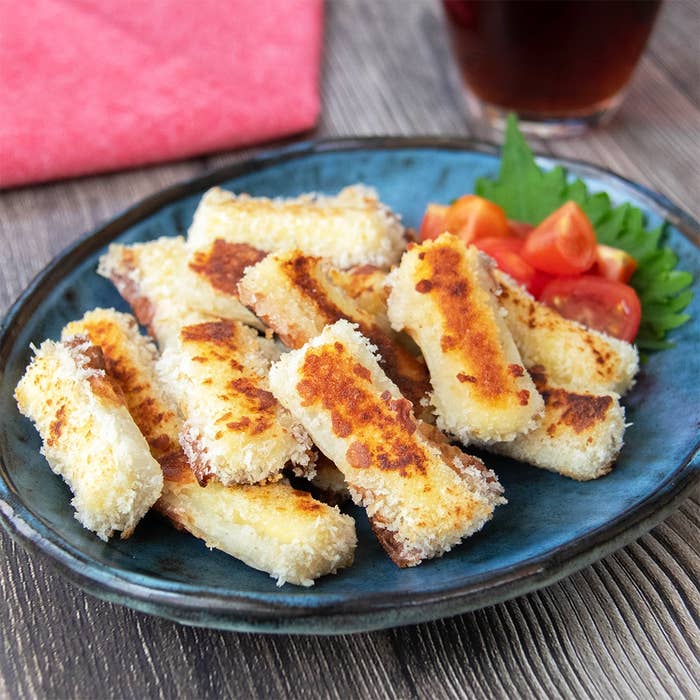 揚げずに焼いて作れるチーズを入れたちくわのフライが皿に盛られている。付け合わせのミニトマトと大葉がある。