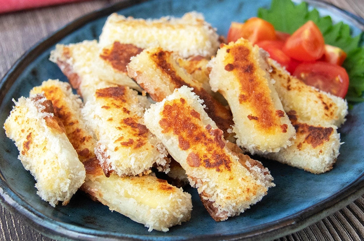 揚げずに焼いて作れるチーズを入れたちくわのフライが皿に盛られている。付け合わせのミニトマトと大葉がある。