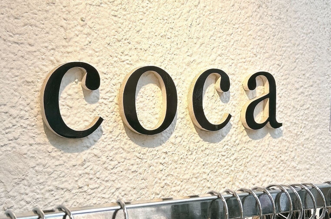 壁に「coca」と書かれた看板があり、下には商品が並んでいる。