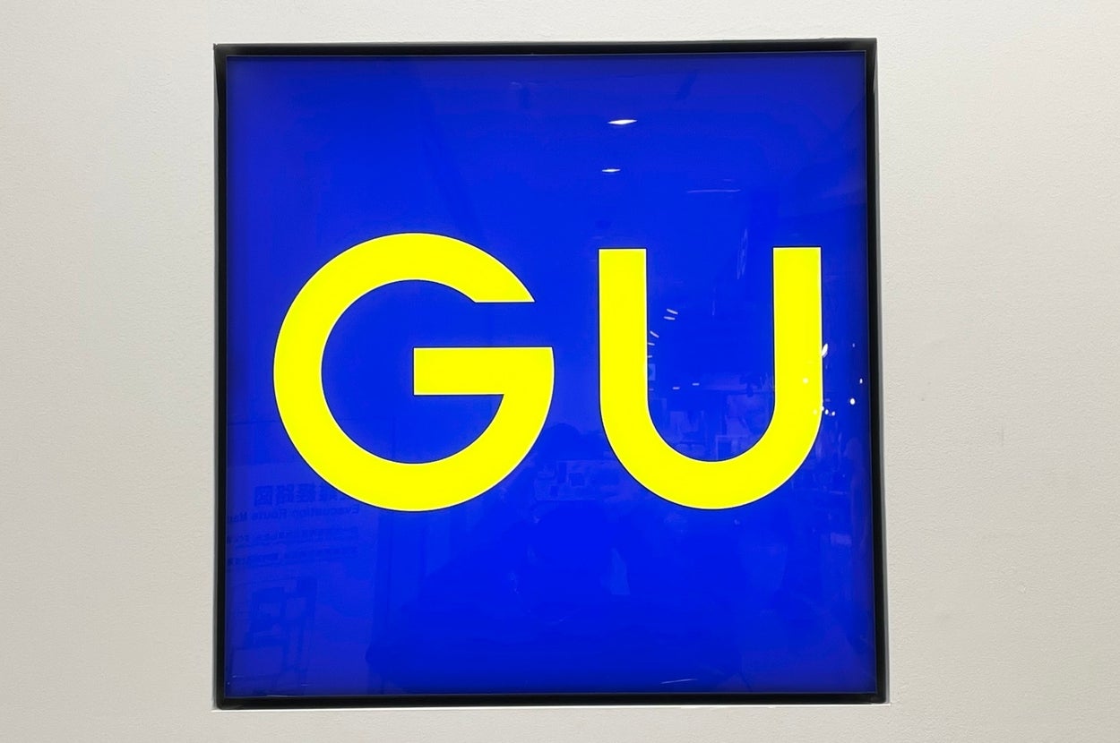 Square sign with large "GU" letters in bold font, centered on a bright background