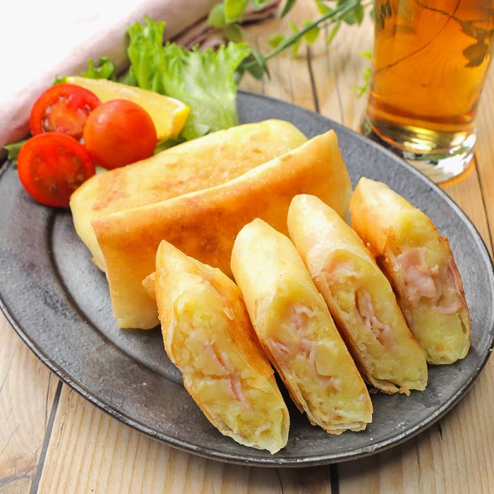 皿に盛られた揚げ春巻きと野菜の添え物。飲み物が傍らにあり、食事の場面を示している。