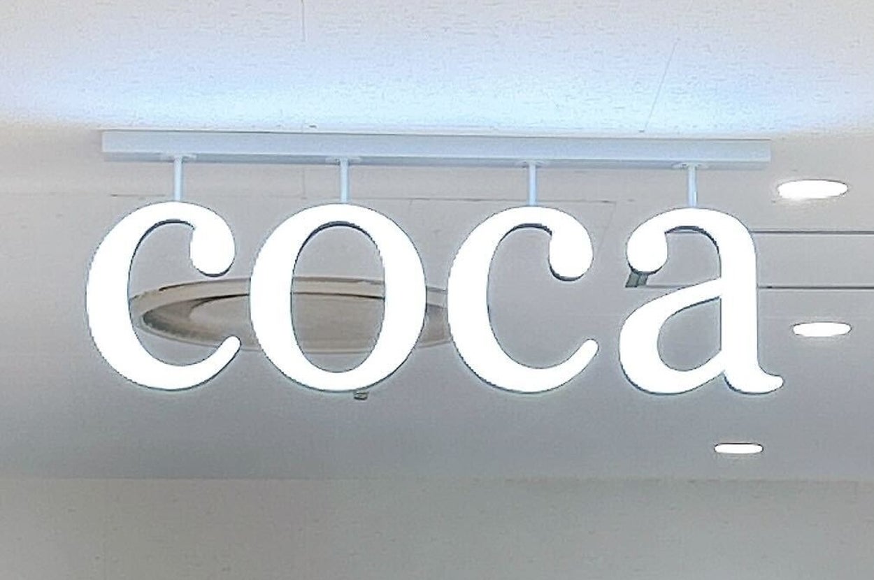 ショップの店内に「coca」と書かれた看板が天井から吊るされています。