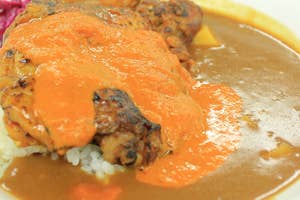 カレーライスにチキンと鮮やかなソースがトッピングされている食欲をそそる一皿。