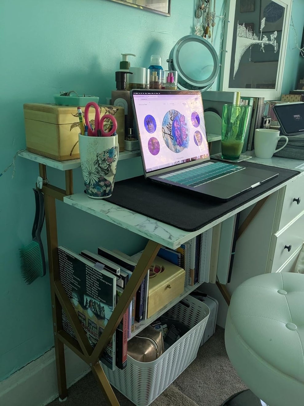 A stylish home office desk setup featuring a laptop displaying colorful graphics, books, and decorative items