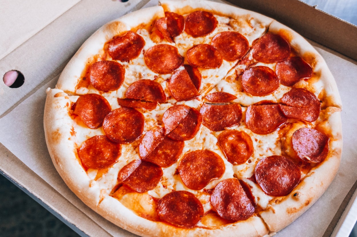 Pepperoni pizza in an open box, featuring a golden crust and evenly spread slices of pepperoni