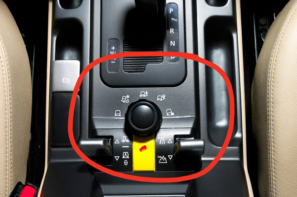 Car center console with gear shift, two cup holders, and various control buttons visible, viewed from above