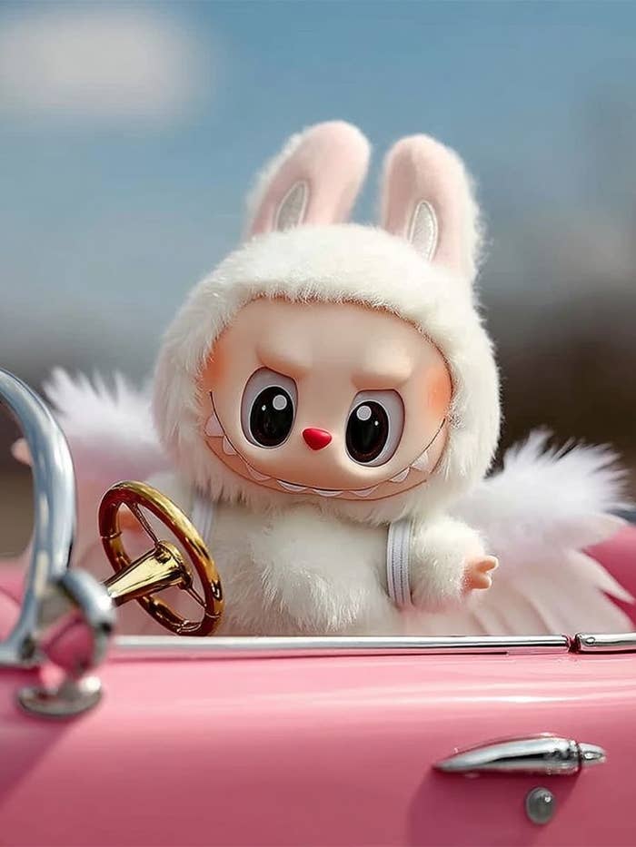 Un muñeco peludo con capucha de conejo conduce un pequeño coche convertible