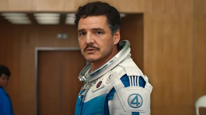 Persona con traje espacial, estilo moderno y futurista, con un número 4 visible en el brazo. Fondo con paredes de madera