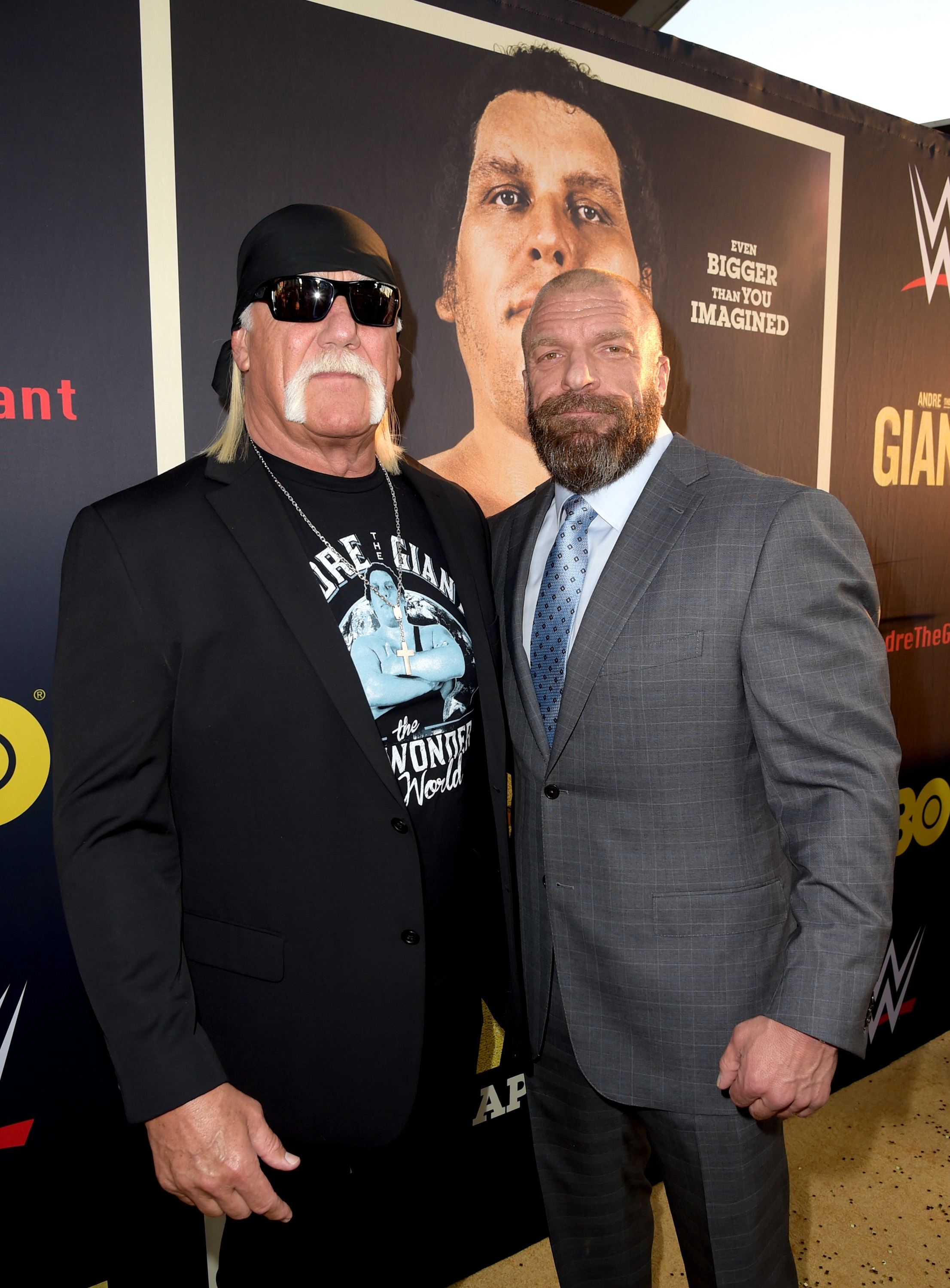 Hulk Hogan and Triple H together in front of a backdrop with WWE logos