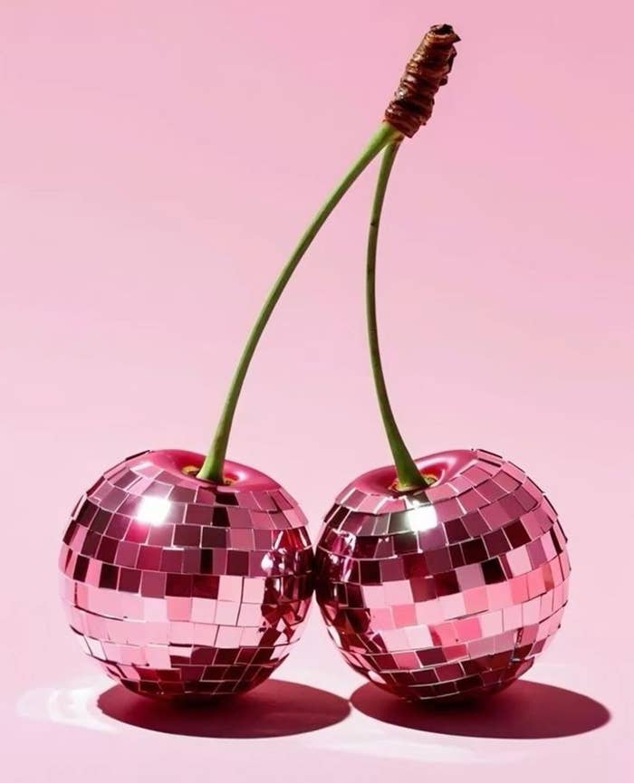 Two cherries with disco ball surfaces connected by stems, set against a plain background