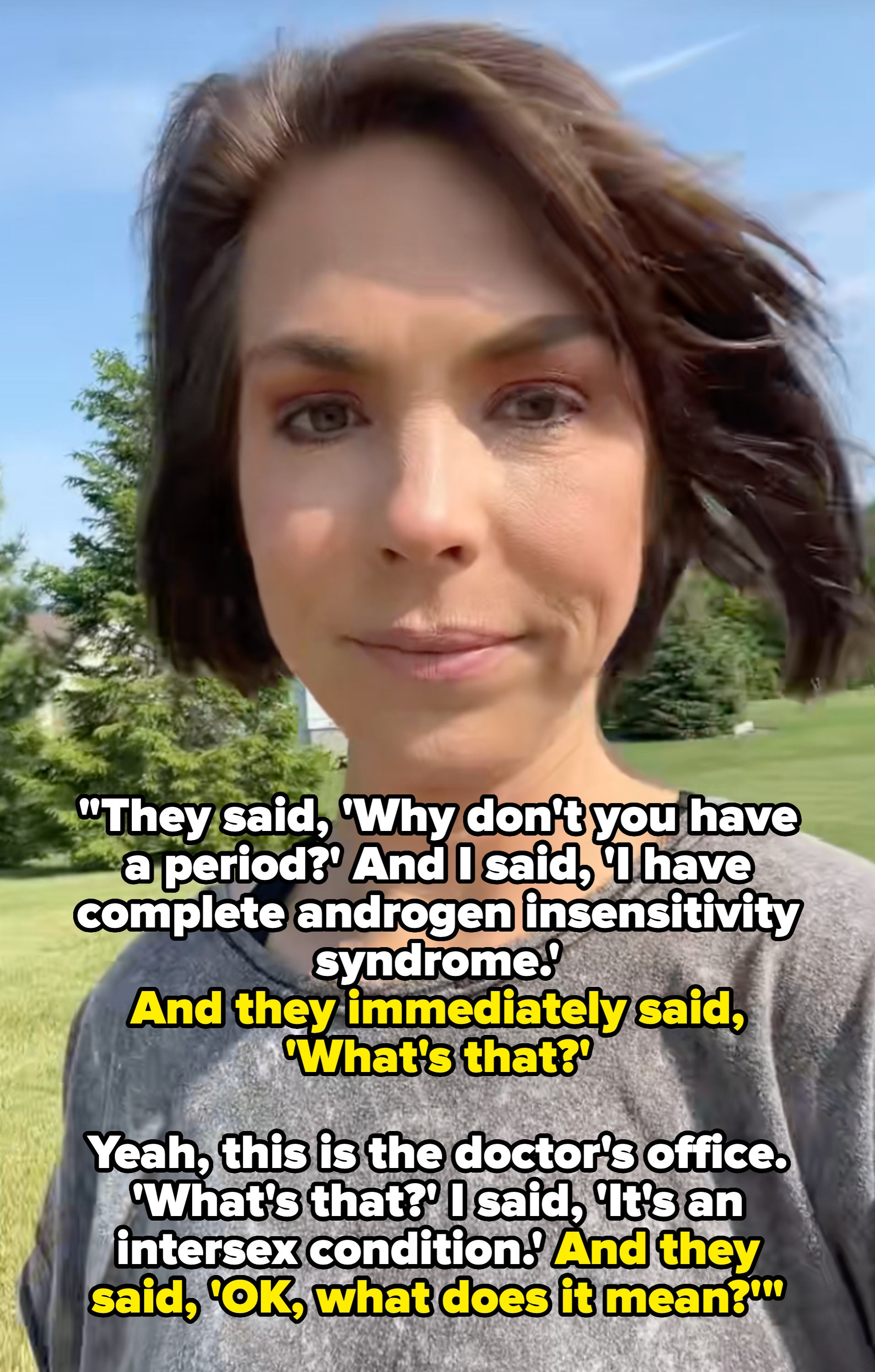 Person utendørs med kort hår iført en uformell topp. Trær og et hus i bakgrunnen