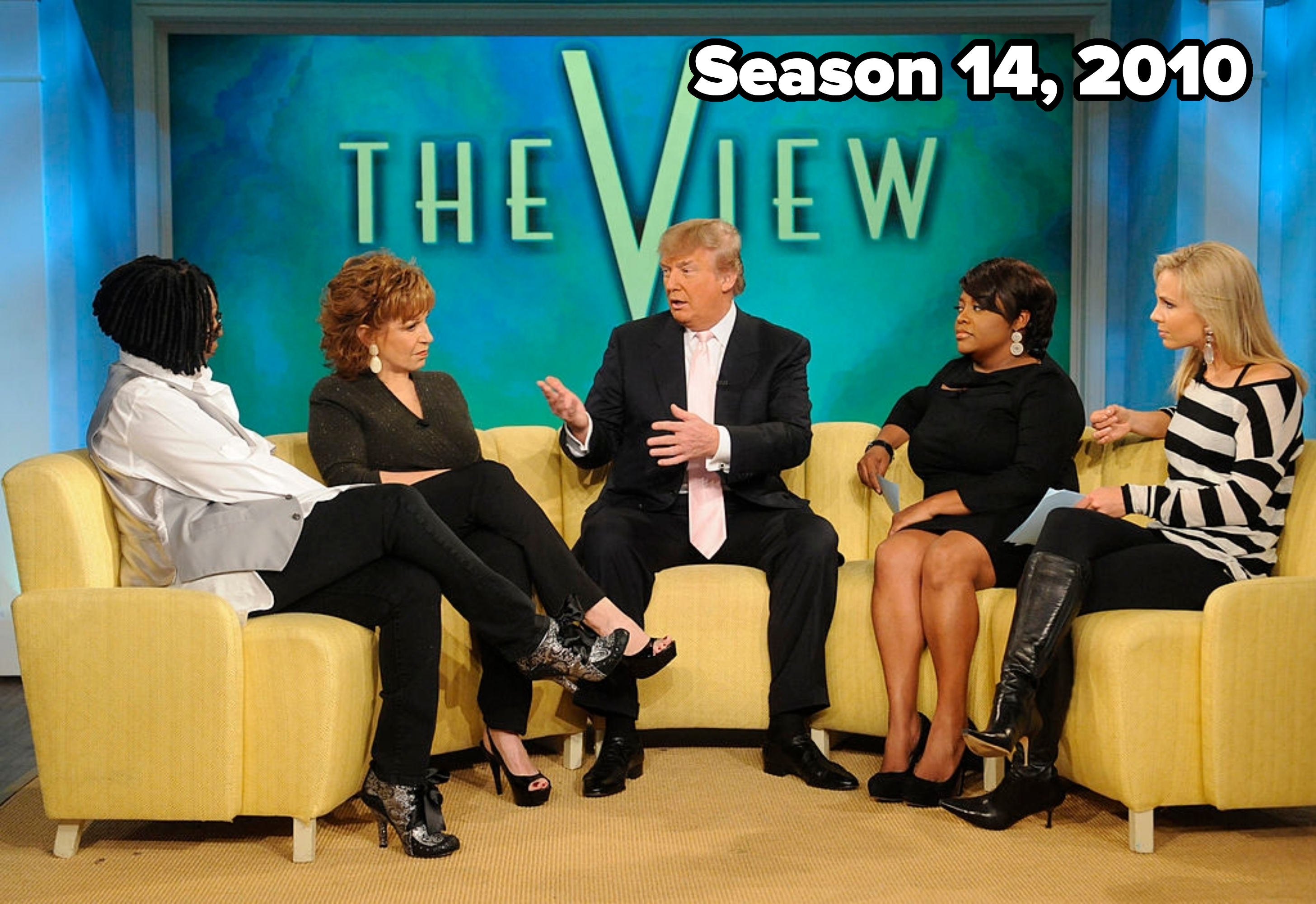 Five people are seated on a talk show set&#x27;s couch engaged in conversation