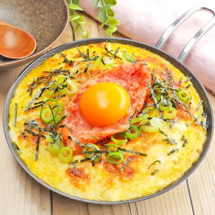 料理は鉄鍋に入ったフワフワの長芋料理。中央に生卵、明太子、刻みねぎ、のりがトッピング。