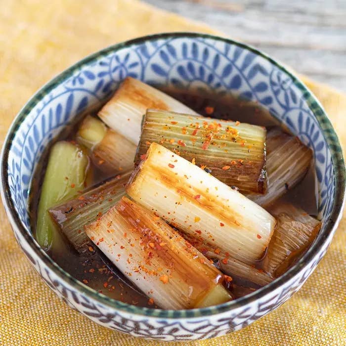 器に盛られた焼きネギの料理。細かい唐辛子が上に振りかけられ、風味をそそる。