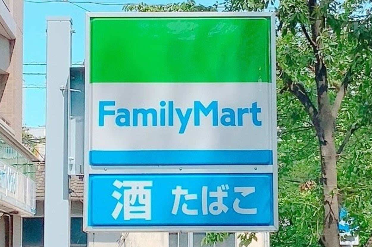 ファミリーマートの看板に「酒」「たばこ」と表示されています。背景に建物があります。