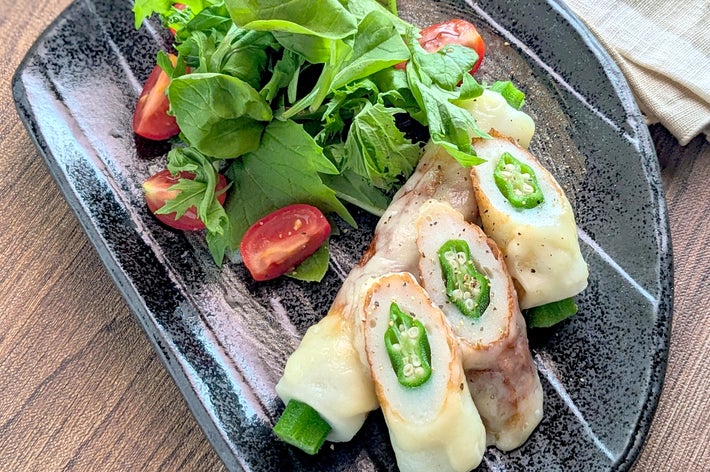 料理の写真。豚肉で巻かれたチーズと青唐辛子の串焼きが皿に盛られ、横にサラダが添えられている。