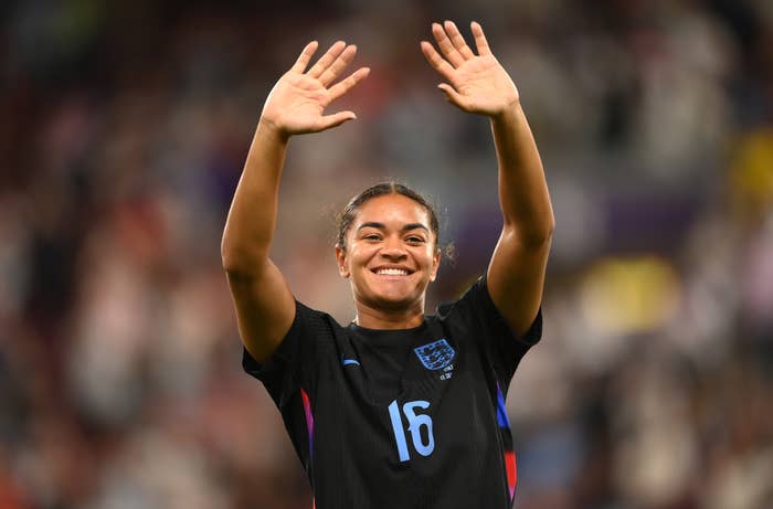 Person in a sports jersey, smiling and waving to a crowd