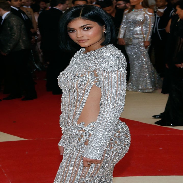 Kylie Jenner in a fitted, embellished gown with intricate detailing on a red carpet