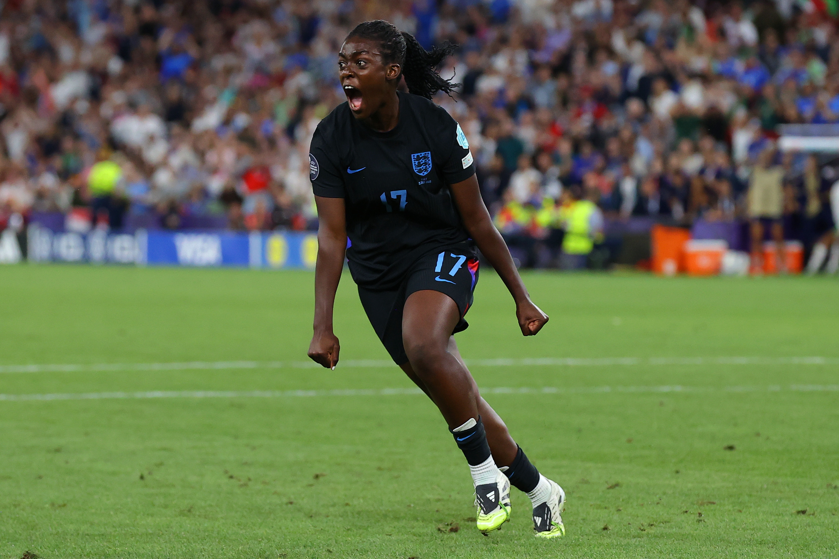 Soccer player celebrating on the field, wearing a black jersey with "17." Crowd blurred in the background